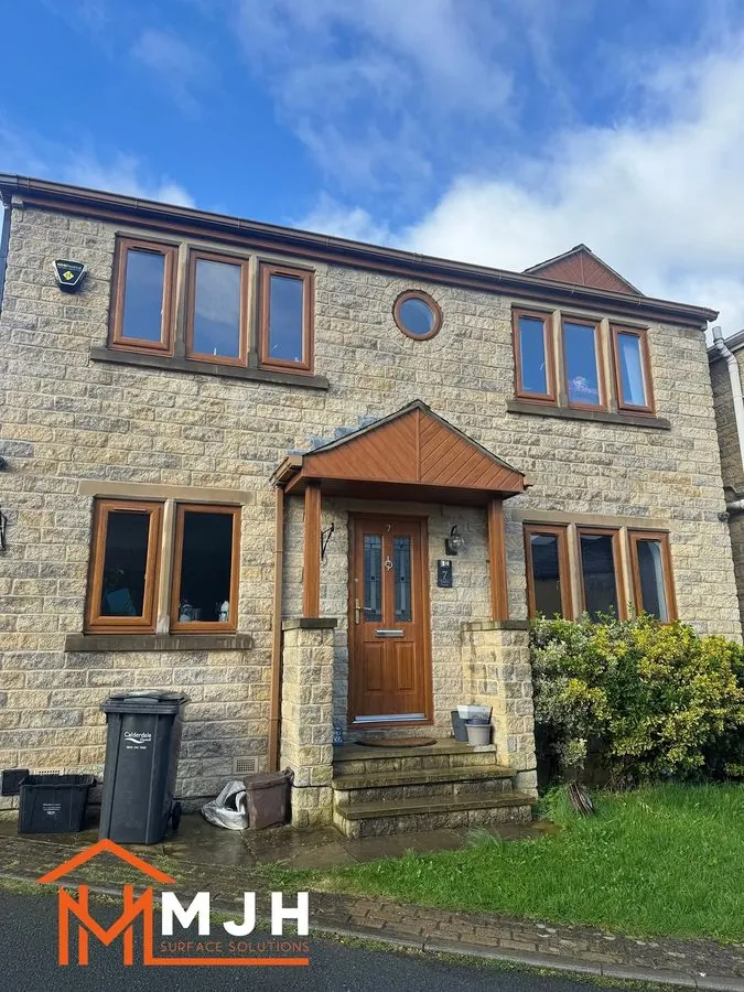 Stone house with brown wood-effect window frames and a brown front door before spraying