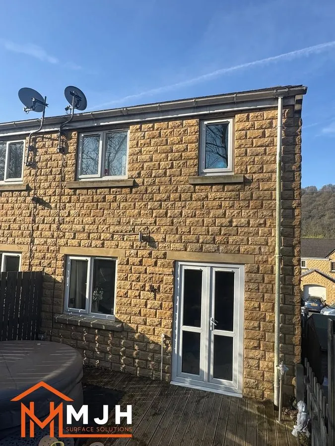 Stone house with white uPVC windows and French doors before spraying