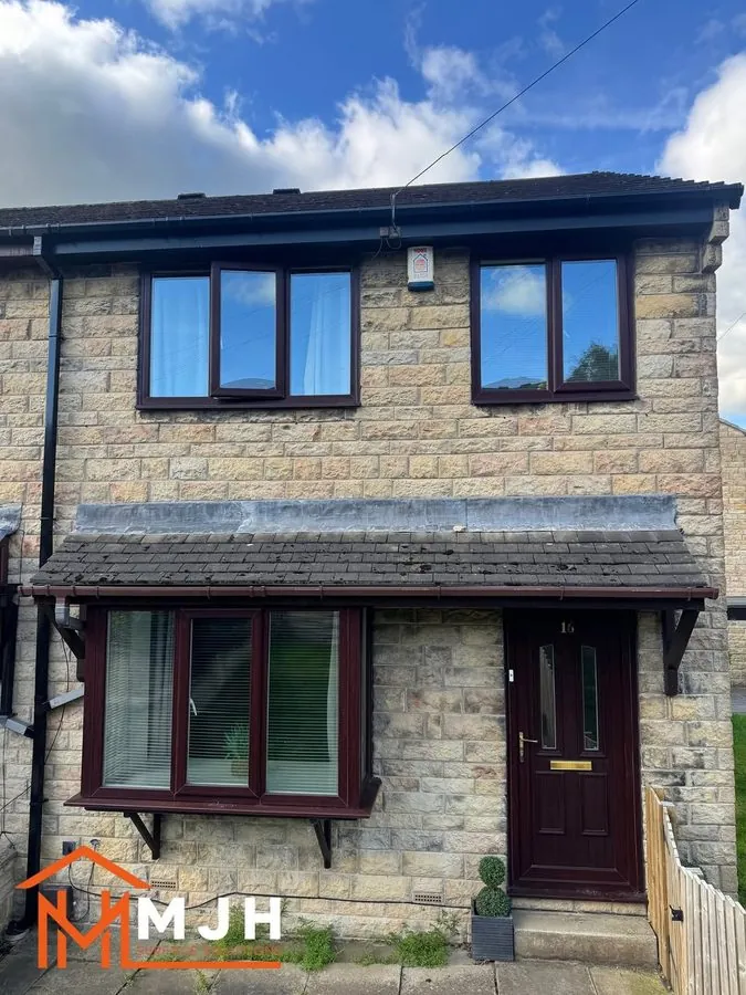 Stone semi with a maroon front door before spraying