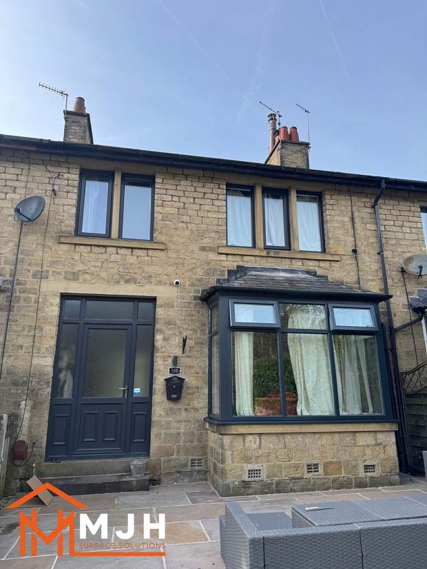 Stone terraced house after spraying, with the bay window in anthracite grey