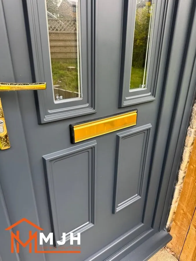 Close-up of a sprayed grey front door with brass letterplate and handle
