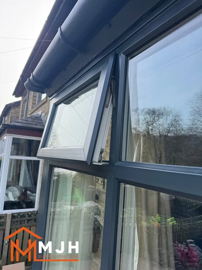 Close-up of a sprayed anthracite window frame with the top opener ajar
