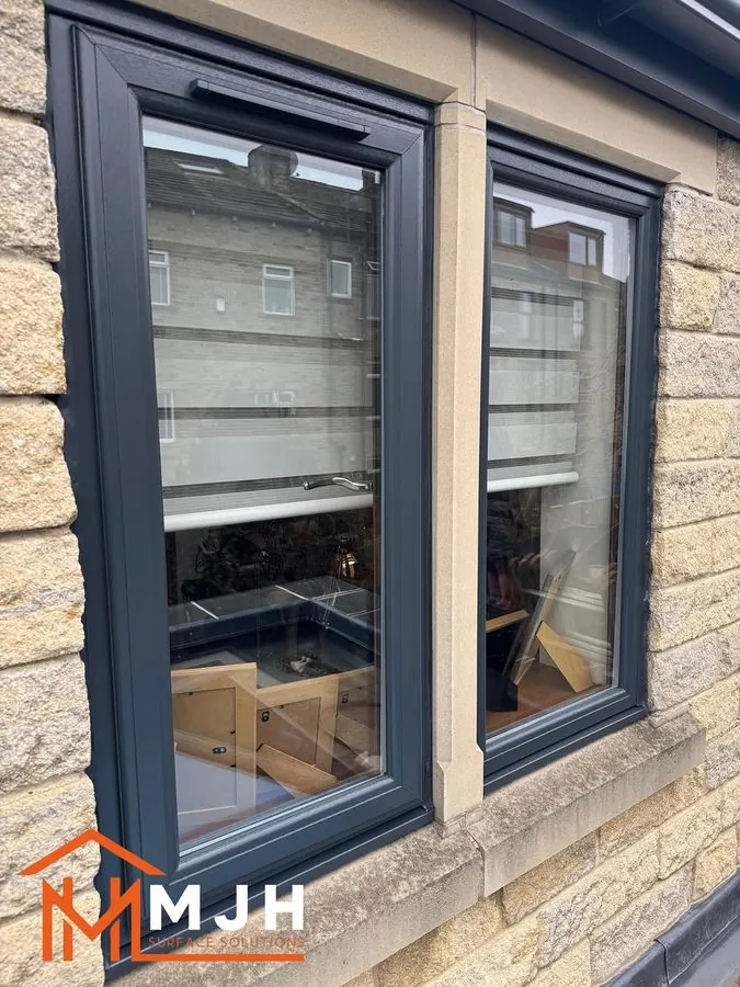 Close-up of sprayed anthracite window frames on a stone house